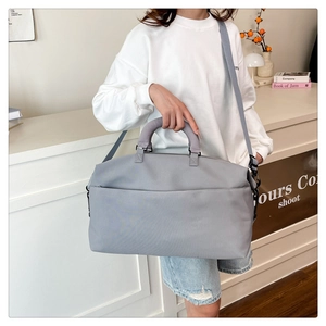Close-up of light gray travel bag with padded handle and detachable woven shoulder strap