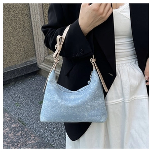 Detail of light blue denim hobo bag with beige leather strap and bow decoration