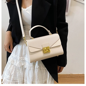 Dettaglio trama intrecciata e fibbia dorata su borsa strutturata color crema chic