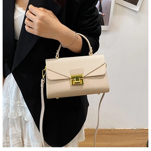 Dettaglio borsa beige con chiusura dorata quadrata e patta in pelle con trama intrecciata