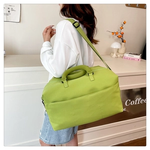 Detail view of water-resistant green travel bag with adjustable strap and sturdy handles