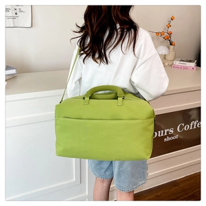 Rear view of a model carrying a large lime green travel bag with wide shoulder straps