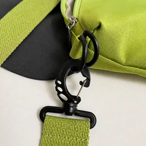 Vue détaillée du mousqueton en métal noir et de la sangle tissée sur le sac de voyage vert