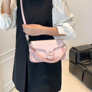 Pink checkered crossbody bag with silver C-buckle and woven handle on model