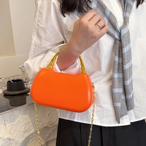 Orange cat-ear handbag with golden bamboo handle and chain strap worn by a model