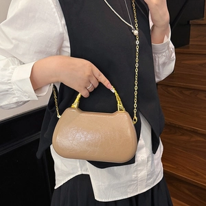 Chic beige box bag with bamboo handle and gold chain strap shown on a model