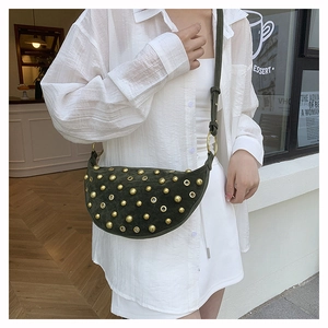 Detail of dark green saddle bag featuring gold studs and adjustable shoulder strap
