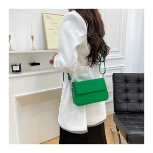 Détail d'un sac bandoulière vert vif avec crochets en métal argenté et logo discret