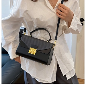 Dettaglio dell'elegante borsa nera con trama a serpente e chiusura a T in metallo dorato