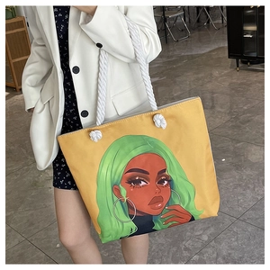 Detail of yellow canvas tote bag with cartoon portrait print and white rope handles