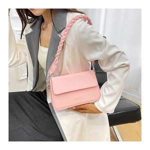 Détail d'un sac à bandoulière en cuir rose avec poignée tressée porté par un mannequin