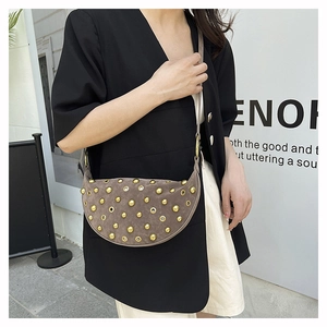 Close-up of studded half-moon crossbody bag with vintage leather and gold metal eyelets