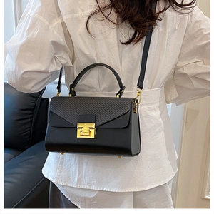 Borsa quadrata nera alla moda con fibbia dorata indossata da modella in camicia