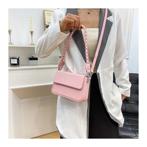 Détail d'un sac boîte en cuir mat rose avec poignée tressée et bandoulière