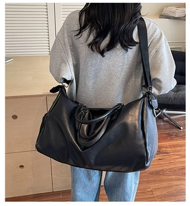 Detail of a large black PU leather travel bag showing the texture and body proportions