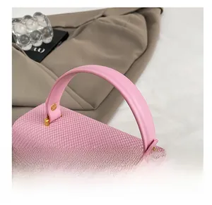 Dettaglio della trama rosa intrecciata e del manico in pelle liscia con fibbia dorata