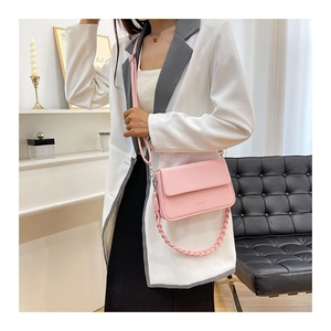 Détail du sac boîte rose clair avec chaîne en cuir tressé et bandoulière réglable