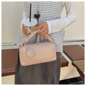 Detail of light pink Boston bag with lychee texture and pleated handle decoration