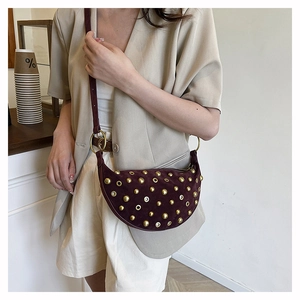 Detailed close-up of dark wine red suede half-moon bag with golden metal rivets