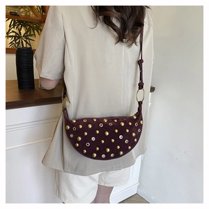 Detail view of burgundy suede crescent bag with gold rivets and metallic eyelets