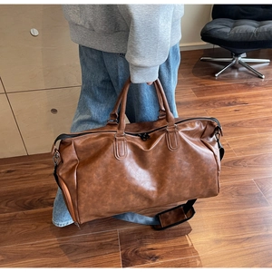 Close-up of vintage brown leather travel bag featuring adjustable strap and metal buckles