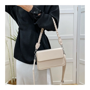 Détail du sac à bandoulière beige avec poignée tressée et fine sangle en cuir