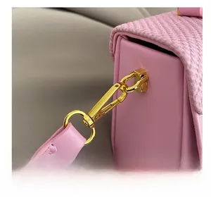 Dettaglio della borsa rosa con gancio in metallo dorato e trama della patta intrecciata