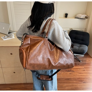 Detail view of large brown vintage travel bag showing side zipper and adjustable shoulder strap