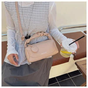 Nude leather Boston bag with pleated handle and strap shown in a lifestyle setting