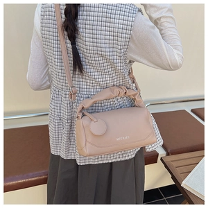 Detail of light beige Boston bag with ruched handle and leather texture on a woman