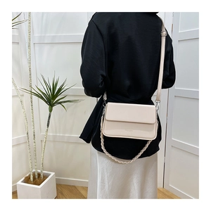 Vue détaillée d'un sac boîte crème avec double bandoulière porté par un mannequin
