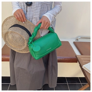 Detail of green Boston bag with litchi texture and ruched handle in outdoor light