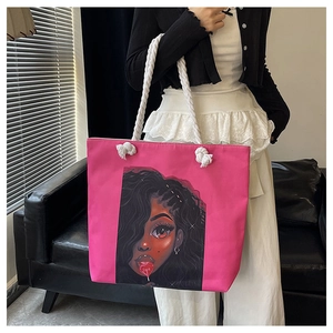 Close-up of pink canvas tote bag with black girl illustration and white rope handles