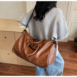 Detailed back view of a vintage brown leather travel bag worn with adjustable strap