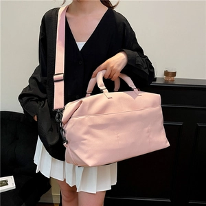 Pink waterproof travel duffel bag with shoulder strap worn by a woman for fitness