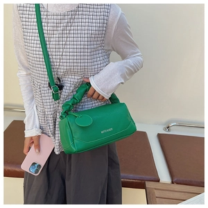 Detail of green Boston bag with lychee texture leather and pleated cloud-style handle