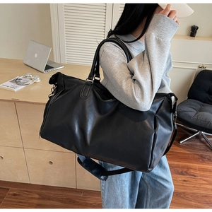 Detail of black leather travel bag with adjustable strap and sturdy metal hardware