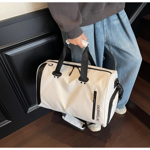 Bolso de viaje grande beige con asas negras sostenido a mano en interior moderno