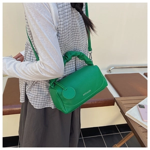 Detailed side view of green pebble leather Boston bag with pleated handle and round charm