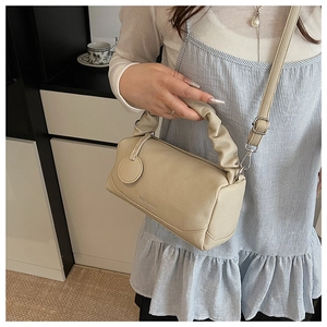 Close-up of beige lychee grain Boston bag featuring pleated handles and embossed logo