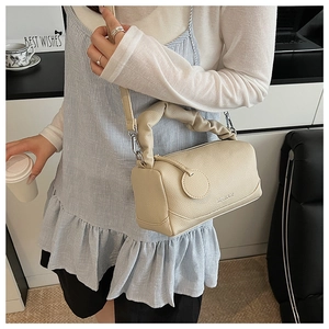 Detail of beige litchi leather Boston bag showing pleated handle and brand logo