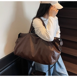 Deep brown vintage leather travel bag with adjustable strap shown on a model on stairs