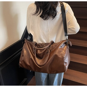 Detail of dark brown leather travel bag with adjustable strap on a male model
