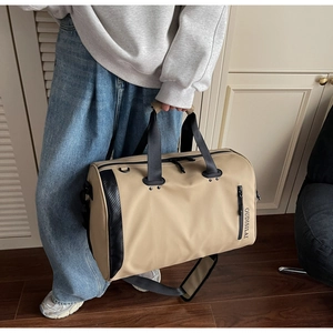 Detalle del bolso de viaje beige con logo OUDISILAI y correa acolchada ajustable