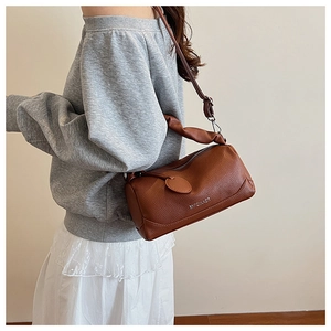 Brown lychee leather boston bag side view on model with white brand lettering