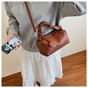 Brown lychee leather Boston bag with ruched handle and brand logo on shoulder strap