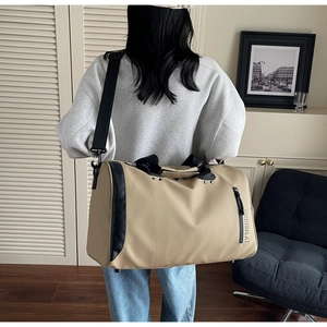 Detalle de bolsa de viaje beige grande con bolsillo vertical de cremallera y asas negras fijas