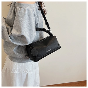 Detail of black Boston bag with scrunchie handle and white logo on litchi leather