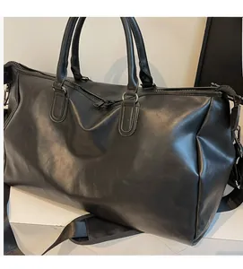 Detail view of large black leather travel bag with durable handles and adjustable strap