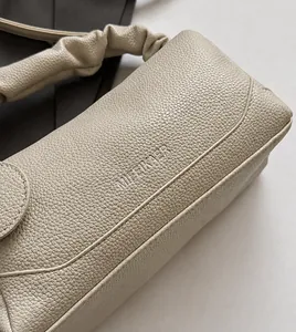 Close-up of beige pebble leather handbag with pleated cloud handle and MIFEIKAER logo